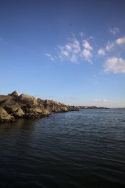 Gün batımında açık ve güneşli bir günde sahil kenarında dalgalı su.