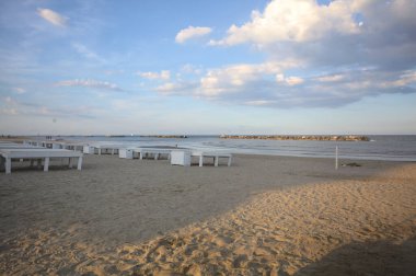 Gün batımında gölgede sahildeki boş iskemleler.