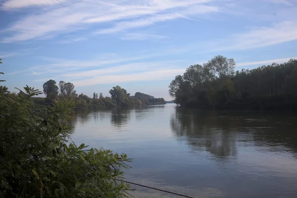 İtalya 'nın kırsal kesimlerinde kısmen bulutlu bir günde sudaki ağaçlarla çevrili bir nehir.