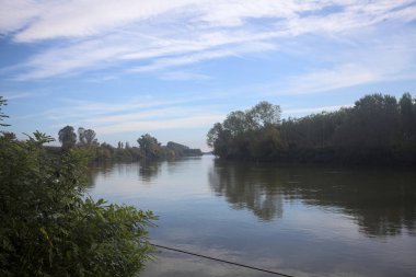 İtalya 'nın kırsal kesimlerinde kısmen bulutlu bir günde sudaki ağaçlarla çevrili bir nehir.