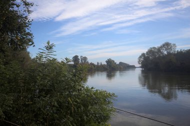 İtalya 'nın kırsal kesimlerinde kısmen bulutlu bir günde sudaki ağaçlarla çevrili bir nehir.