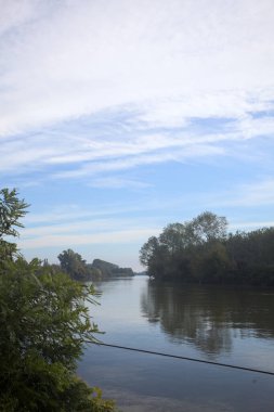 İtalya 'nın kırsal kesimlerinde kısmen bulutlu bir günde sudaki ağaçlarla çevrili bir nehir.