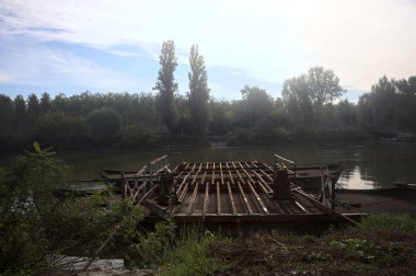 İtalya 'nın kırsal kesimlerindeki sulara dökülen gökyüzü ve kıyıları olan bir nehirde iki tekneyle yapılmış bir sal.