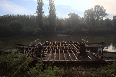 İtalya 'nın kırsal kesimlerindeki sulara dökülen gökyüzü ve kıyıları olan bir nehirde iki tekneyle yapılmış bir sal.
