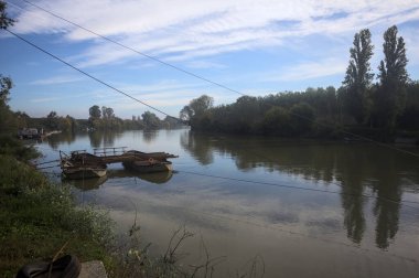 İtalya 'nın kırsal kesimlerindeki sulara dökülen gökyüzü ve kıyıları olan bir nehirde iki tekneyle yapılmış bir sal.