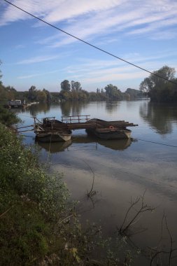 İtalya 'nın kırsal kesimlerindeki sulara dökülen gökyüzü ve kıyıları olan bir nehirde iki tekneyle yapılmış bir sal.