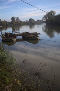 İtalya 'nın kırsal kesimlerindeki sulara dökülen gökyüzü ve kıyıları olan bir nehirde iki tekneyle yapılmış bir sal.