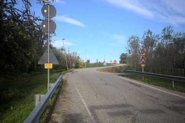 İtalya kırsalında güneşli bir günde ağaçlarla çevrili bir yol.