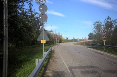 İtalya kırsalında güneşli bir günde ağaçlarla çevrili bir yol.