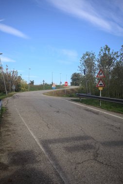 İtalya kırsalında güneşli bir günde ağaçlarla çevrili bir yol.