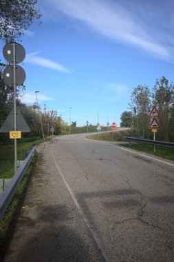 İtalya kırsalında güneşli bir günde ağaçlarla çevrili bir yol.