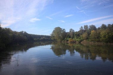 İtalya 'nın kırsal kesimlerinde kısmen bulutlu bir günde sudaki ağaçlarla çevrili bir nehir.