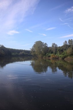 İtalya 'nın kırsal kesimlerinde kısmen bulutlu bir günde sudaki ağaçlarla çevrili bir nehir.