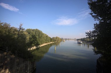 Oyalama kanalı, direkleri olan ve suya gökyüzü düşmüş demirli bir tekne ve sahneyi çerçeveleyen bir ağaç.