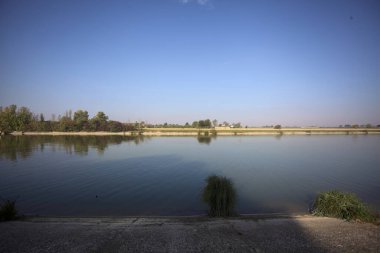 İtalya 'nın uzak bir kırsalında güneşli bir günde nehir kıyısında tarlalar ve kır malikaneleri üzerlerindeydi.