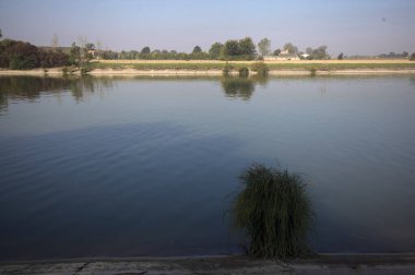 İtalya 'nın uzak bir kırsalında güneşli bir günde nehir kıyısında tarlalar ve kır malikaneleri üzerlerindeydi.