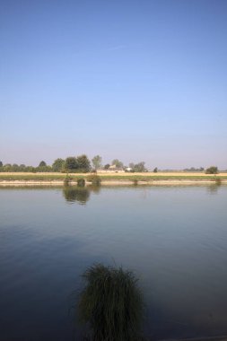 İtalya 'nın uzak bir kırsalında güneşli bir günde nehir kıyısında tarlalar ve kır malikaneleri üzerlerindeydi.