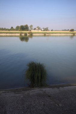 İtalya 'nın uzak bir kırsalında güneşli bir günde nehir kıyısında tarlalar ve kır malikaneleri üzerlerindeydi.