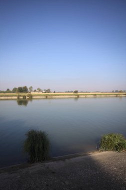 İtalya 'nın uzak bir kırsalında güneşli bir günde nehir kıyısında tarlalar ve kır malikaneleri üzerlerindeydi.