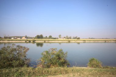 İtalya 'nın uzak bir kırsalında güneşli bir günde nehir kıyısında tarlalar ve kır malikaneleri üzerlerindeydi.