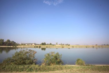 İtalya 'nın uzak bir kırsalında güneşli bir günde nehir kıyısında tarlalar ve kır malikaneleri üzerlerindeydi.