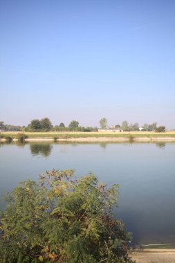 İtalya 'nın uzak bir kırsalında güneşli bir günde nehir kıyısında tarlalar ve kır malikaneleri üzerlerindeydi.