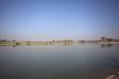 İtalya 'nın kırsal kesimlerinde güneşli bir günde ufuk çizgisi ve köprüsü olan küçük bir ada tarafından yapılan saptırıcı bir kanalda çatal.