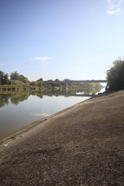 Güneşli bir günde, İtalya kırsalında, yapının ve ağaçların bulunduğu bir köprü.