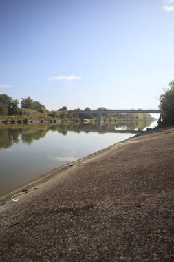Güneşli bir günde, İtalya kırsalında, yapının ve ağaçların bulunduğu bir köprü.