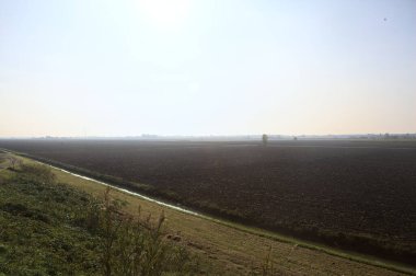 Uzakta bir traktörle güneş tarafından aydınlatılan tarla.