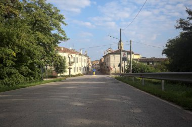 İtalyan kırsalındaki bir köyde caddeye çıkan ağaçlarla çevrili bir yol.