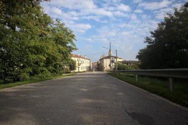 İtalyan kırsalındaki bir köyde caddeye çıkan ağaçlarla çevrili bir yol.