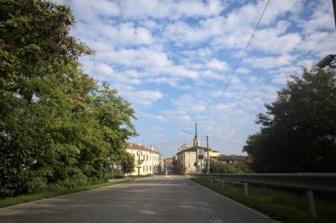 İtalyan kırsalındaki bir köyde caddeye çıkan ağaçlarla çevrili bir yol.