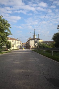 İtalyan kırsalındaki bir köyde caddeye çıkan ağaçlarla çevrili bir yol.