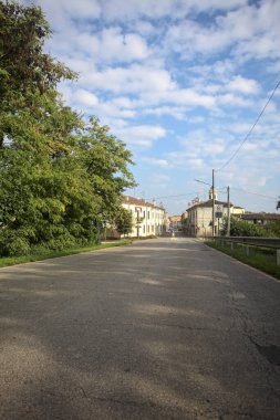 İtalyan kırsalındaki bir köyde caddeye çıkan ağaçlarla çevrili bir yol.
