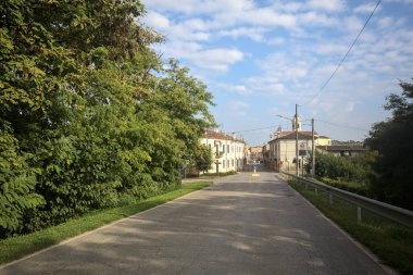 İtalyan kırsalındaki bir köyde caddeye çıkan ağaçlarla çevrili bir yol.