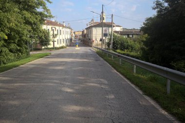 İtalyan kırsalındaki bir köyde caddeye çıkan ağaçlarla çevrili bir yol.