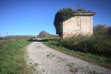 İtalya kırsalındaki bir patikanın kenarındaki çimenlikte terk edilmiş bir bina.