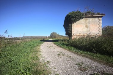 İtalya kırsalındaki bir patikanın kenarındaki çimenlikte terk edilmiş bir bina.