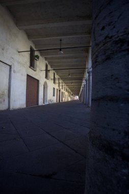 İtalyan kırsalındaki bir köyde, sokağın kenarındaki duvarda ahşap kapılı ve gravürlü veranda.