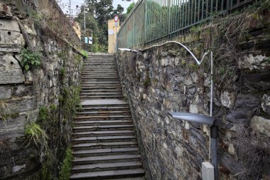 Taş bir duvarın köşesinde merdivenler bir yola çıkıyor.