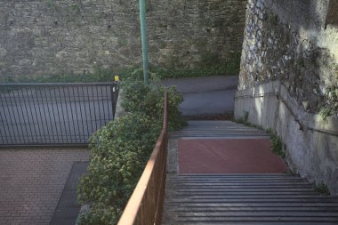 Beton merdiven kenarlarında çimenler, gölgede yolun kenarında.