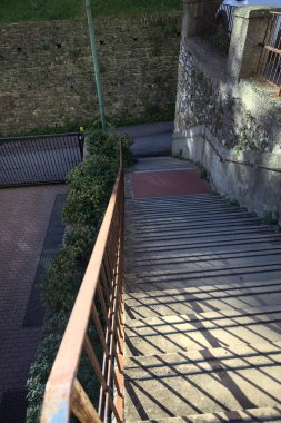 Beton merdiven kenarlarında çimenler, gölgede yolun kenarında.