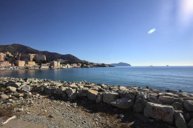 Güneşli bir günde, deniz kenarındaki kayalıklarla dalgalı bir şehir ve uçurumlar.