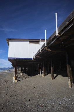 Terk edilmiş tatil köyü binası plajlarda ve sahilde güneşli bir günde taştan bir barajın yanında.