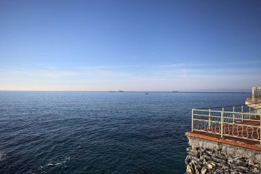 # Gök mavisi bir korkulukla # # Altında deniz olan bir uçurum # # Ve güneşli bir günde # # bir balkonda sarı bir tatil köyü binası #