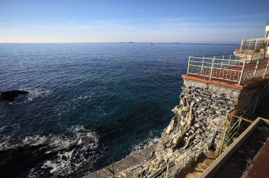 # Gök mavisi bir korkulukla # # Altında deniz olan bir uçurum # # Ve güneşli bir günde # # bir balkonda sarı bir tatil köyü binası #