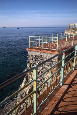 # Gök mavisi bir korkulukla # # Altında deniz olan bir uçurum # # Ve güneşli bir günde # # bir balkonda sarı bir tatil köyü binası #