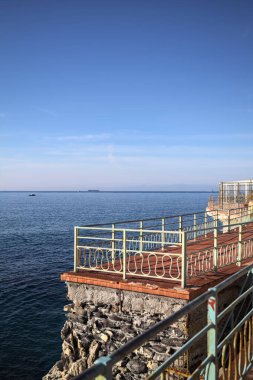 # Gök mavisi bir korkulukla # # Altında deniz olan bir uçurum # # Ve güneşli bir günde # # bir balkonda sarı bir tatil köyü binası #