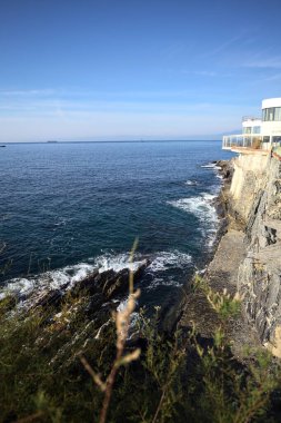 # Gök mavisi bir korkulukla # # Altında deniz olan bir uçurum # # Ve güneşli bir günde # # bir balkonda sarı bir tatil köyü binası #